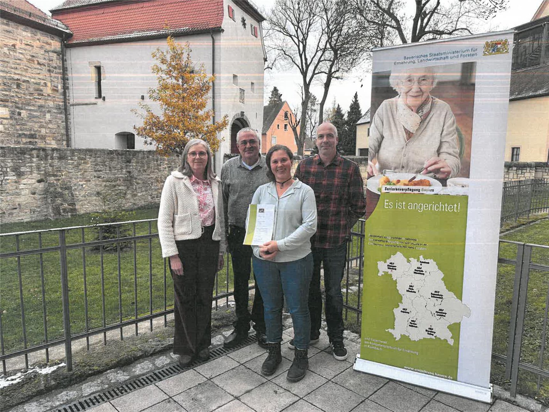 vier Leute mit Zertifikat, daneben Rollup